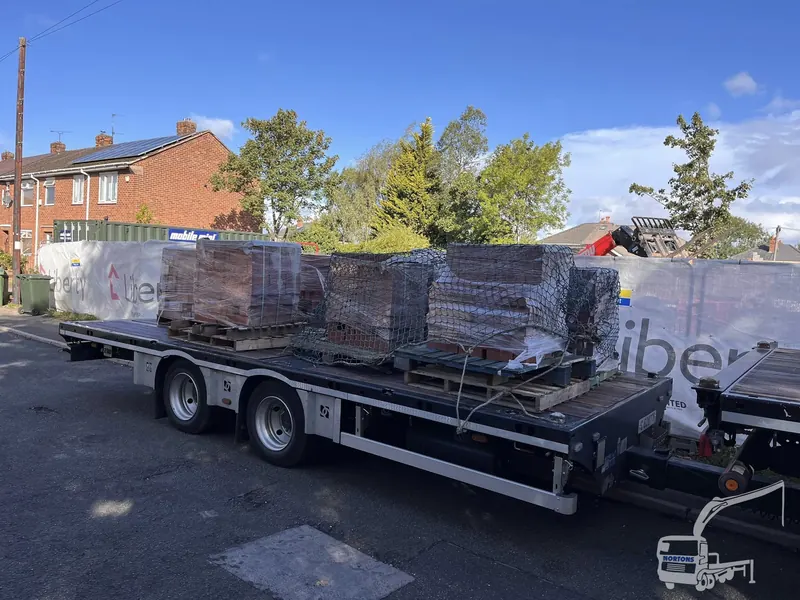Crane offload of brick and block pallets at a construction site