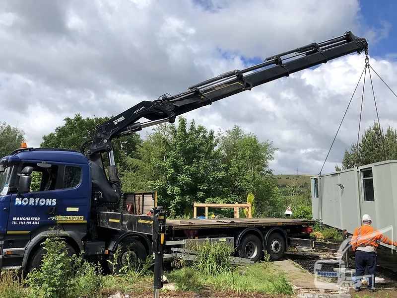 Hiab lorry lifting a cabin onto grounds at a Welsh site