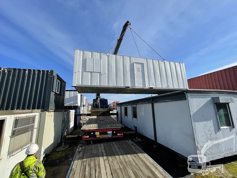 Hiab lorry delivering multiple portable cabins to a site compound