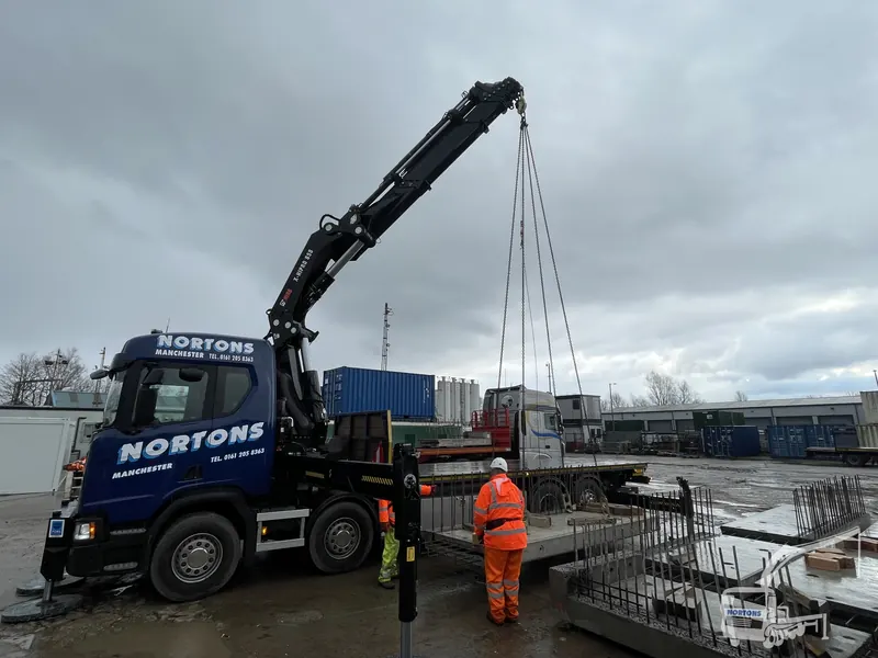 Hiab operator guiding a dockside lift wearing full PPE