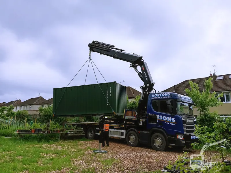 Hiab truck lifting a shipping container into position on a UK site