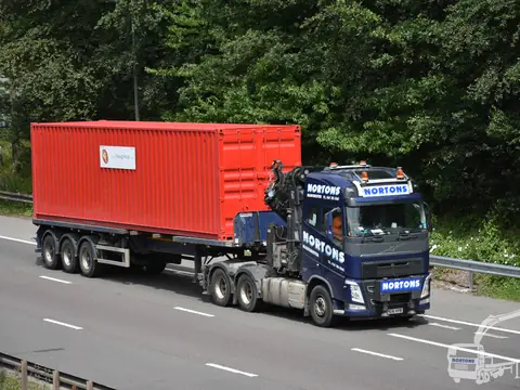 Orange container moved on a low loader along the motorway